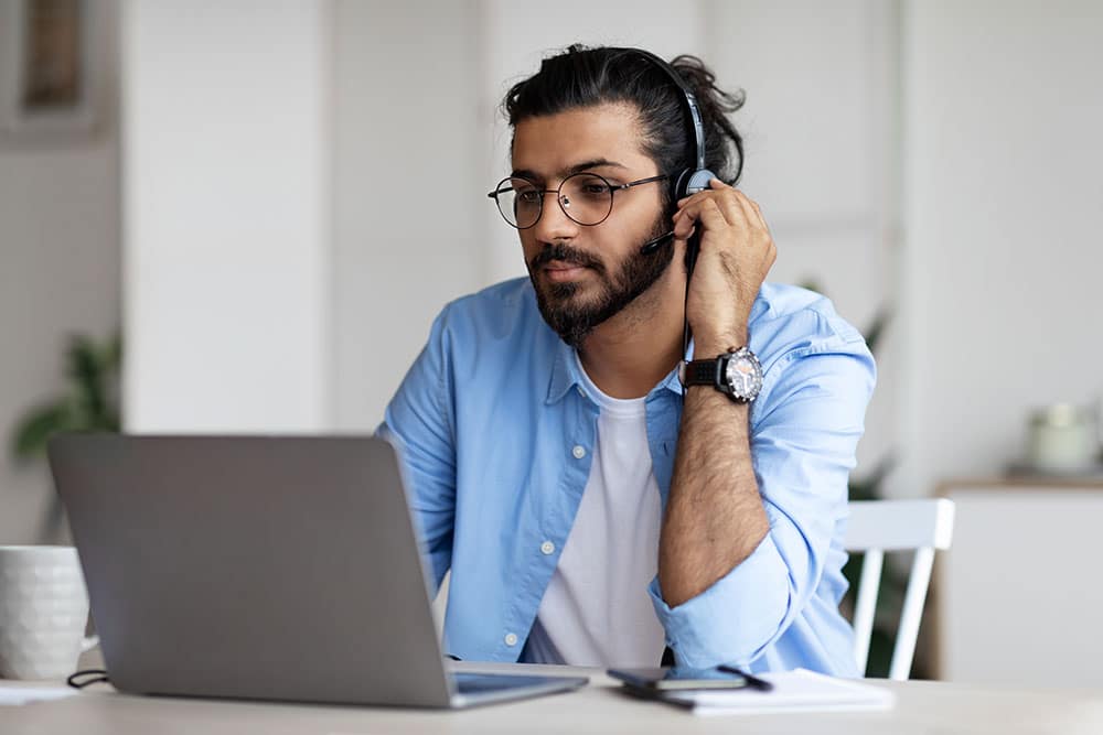 Focused guy in headset watching webinar on laptop