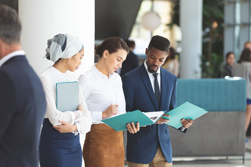 front view of young diverse business people conversing with folders