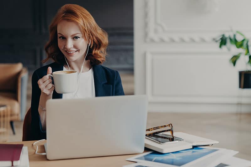 Woman with coffee in front of laptop